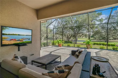 Screened covered sitting area facing trees, fairway, and water